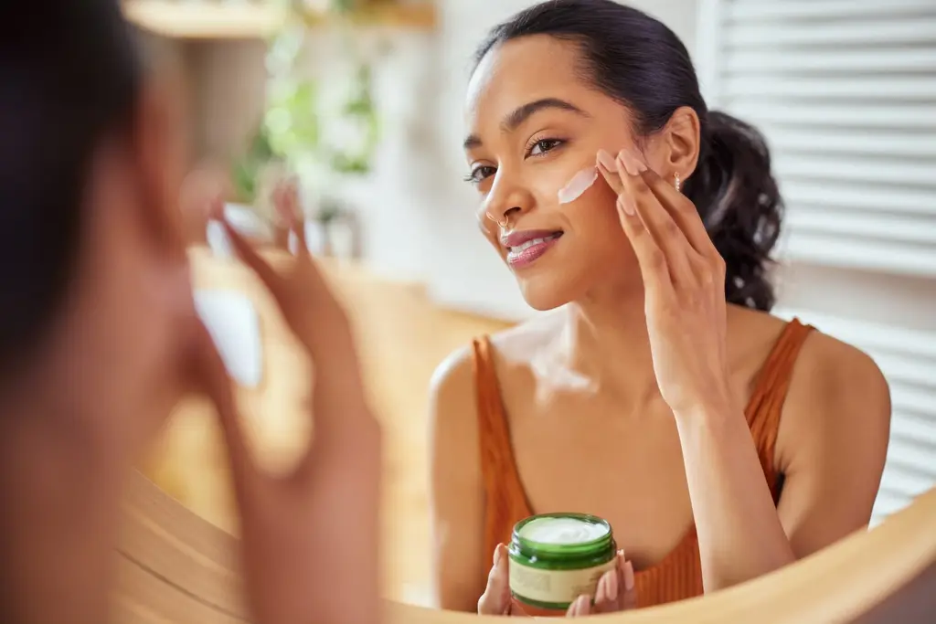 Woman applying face cream during her morning skincare routine, Heliocare products at Dulwich Natural Beauty