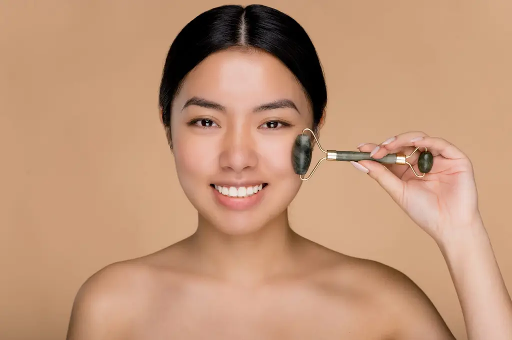 Woman with smooth skin using a jade facial roller, Restylane dermal fillers at Dulwich Natural Beauty London